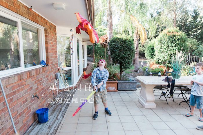Little boy batting at a piñata from a Jurassic Park Dinosaur Birthday Party via Kara